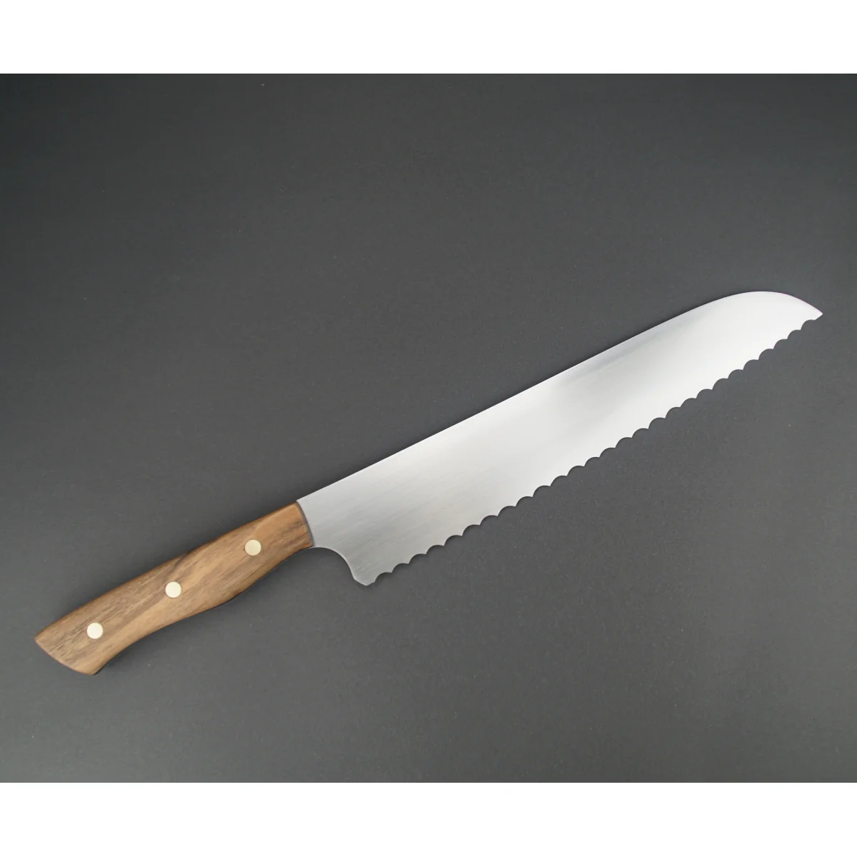 brotmesser-full-tang-kuem-nr25-1-04.webp Handgeschmidetes Brotmesser Nussbaumholz Griff mit Messing Pins